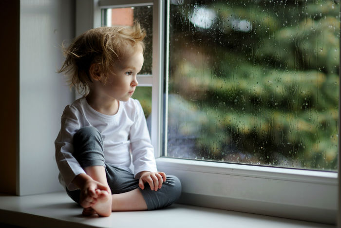 Ребенок грустит у окна
